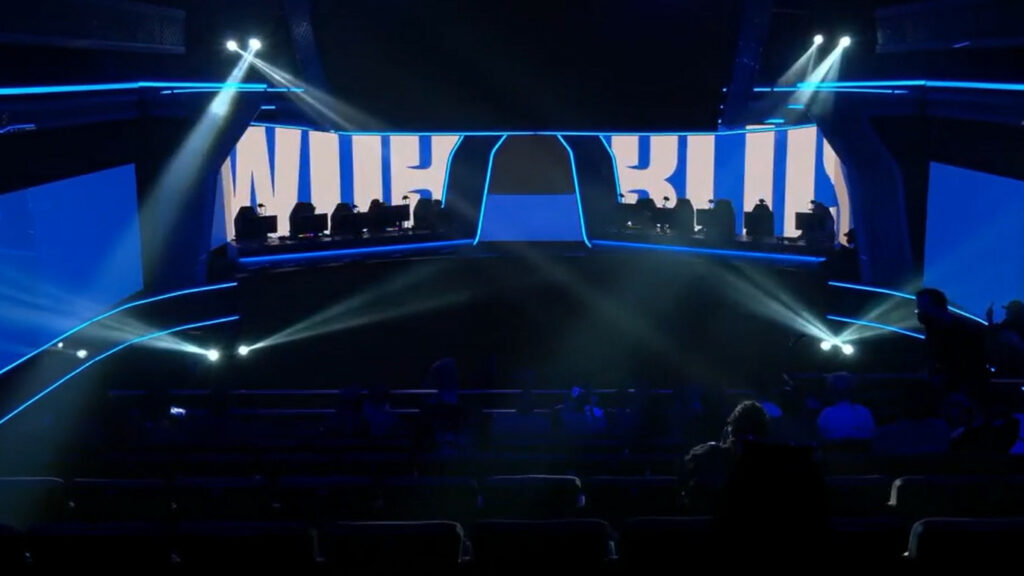 Image showing the broadcast of the Play-In stage for Worlds 2022. The lights are low but the crowd is seen to be very small.