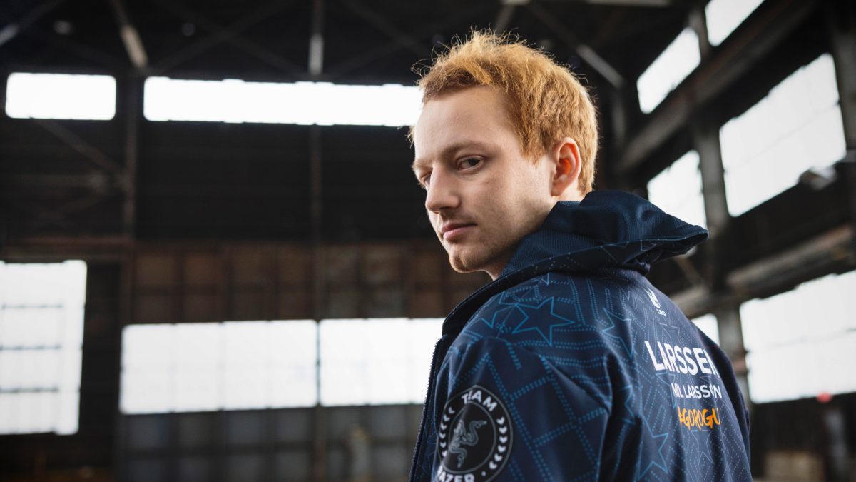 Image shows Rogue player Larssen posing in a windbreaker and look back at the camera over this shoulder