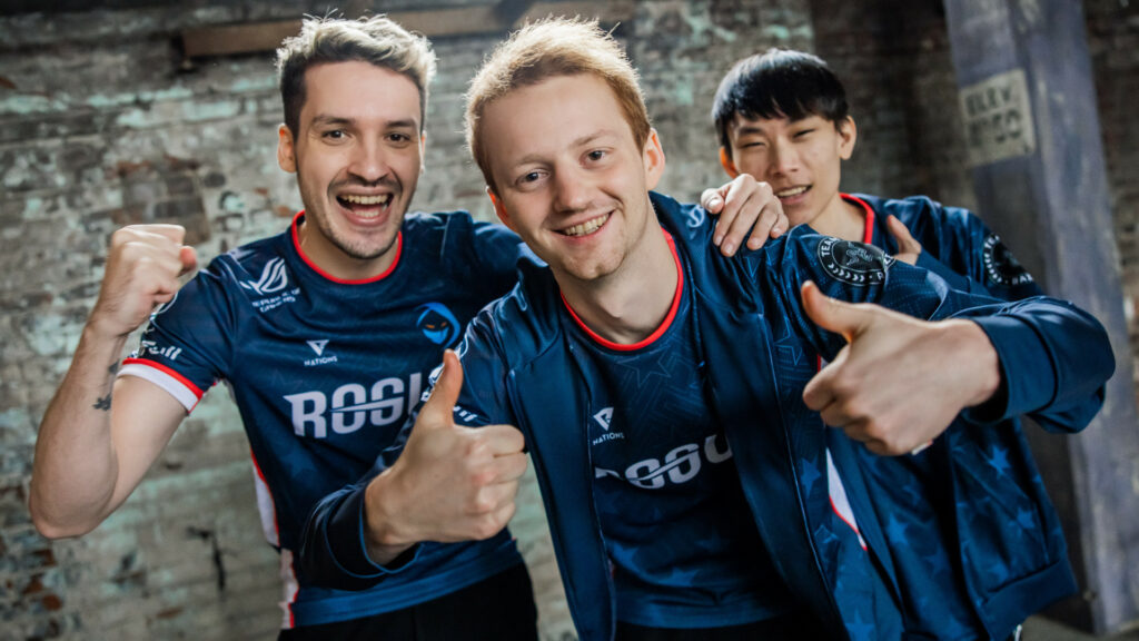 The image shows three players from Rogue. Larssen stands centre frame with Odoamme behind him on his left and Malrang behind him on his right