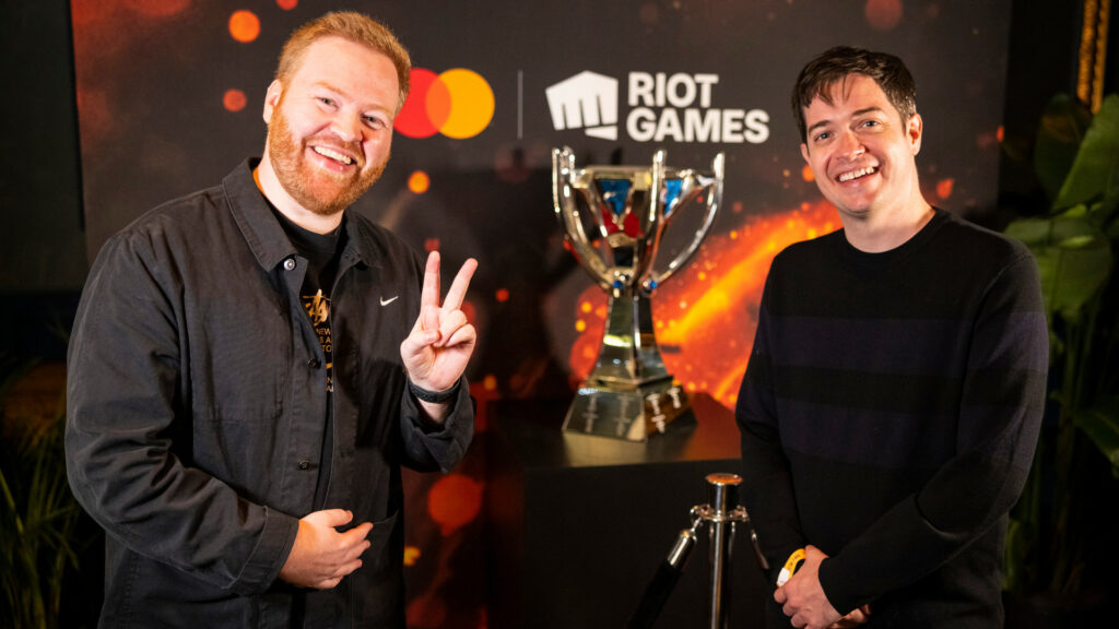 An image shows two Riot Games employees psing with the Summoner's Cup, the trophy for Worlds 2022
